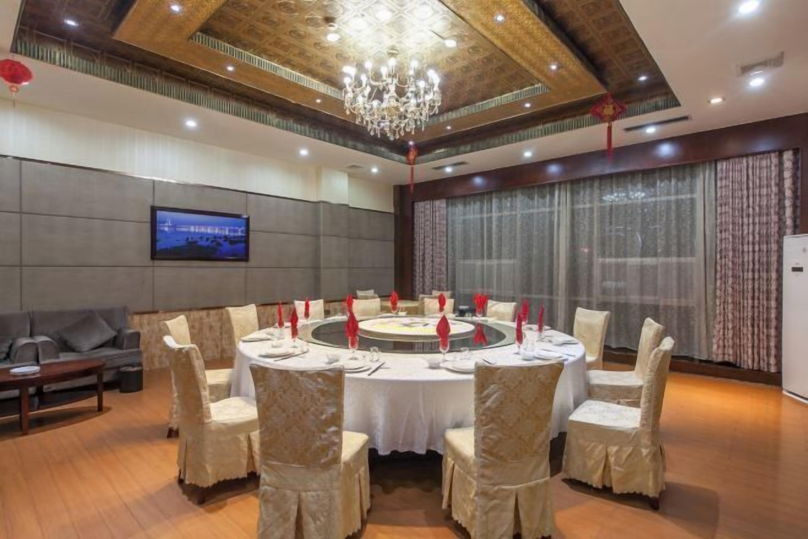Un salón de conferencias con una mesa redonda, mantel blanco y sillas color beige.