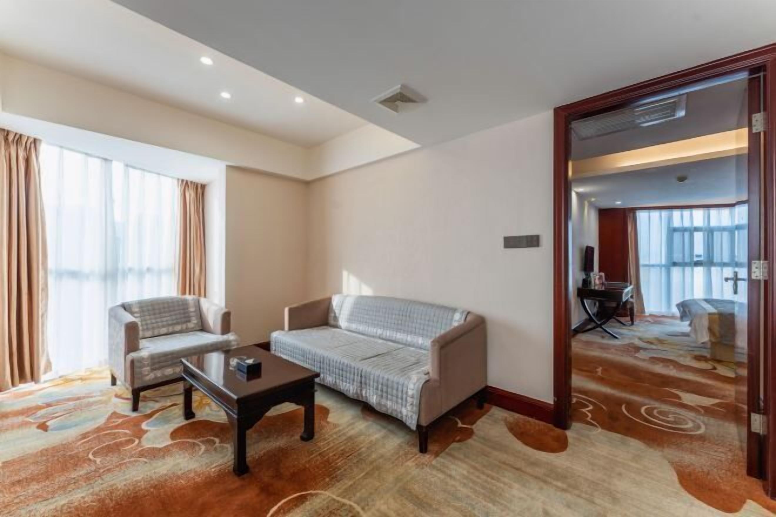 A hotel room with a sofa, armchair, and a small table.