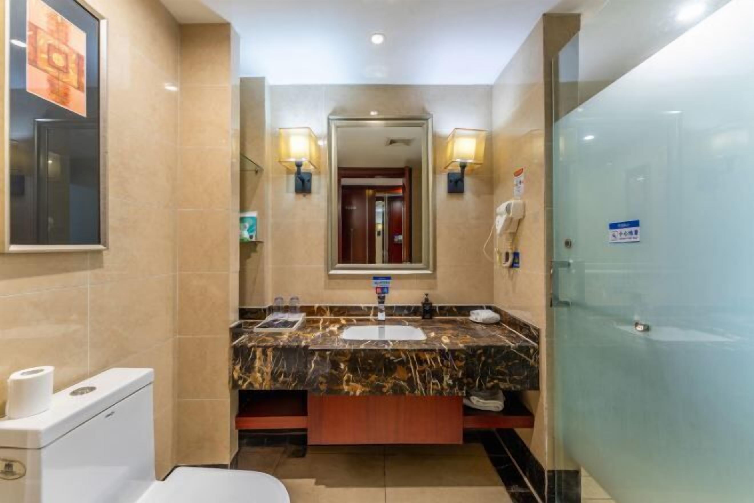 Un baño moderno con un lavamanos de mármol, un inodoro y una cabina de ducha de vidrio.
