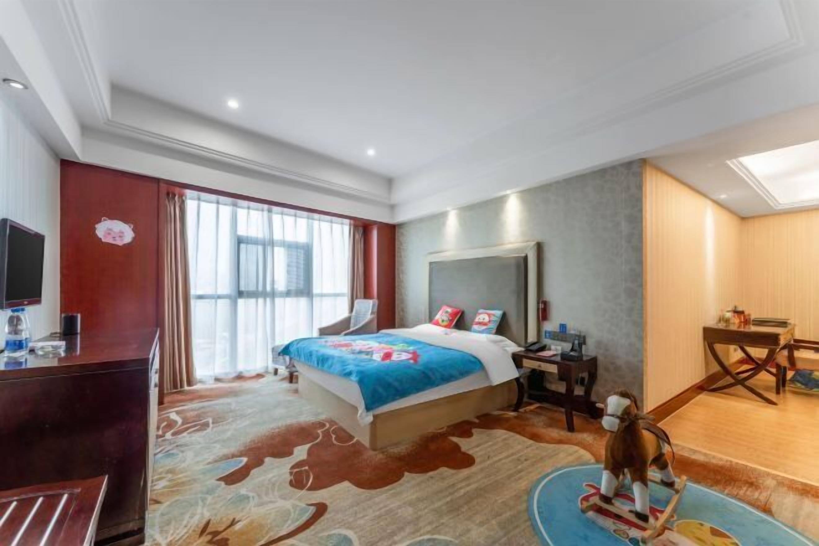 Hotelkamer met een groot bed, een bureau, een stoel, een televisie en een raam met gordijnen.