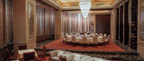A spacious lobby with a round table and chairs, leather sofas, and a chandelier.