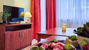 Ein Hotelzimmer mit einem Holztisch, einem Fernseher, einer Lampe, roten Vorhängen und einem Fenster mit Blick.