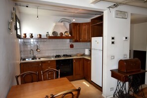Una cucina compatta con mobili in legno, un fornello a gas, un lavandino e un tavolo da pranzo con sedie.
