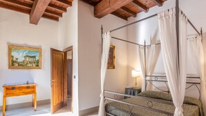 A bedroom with a four-poster bed, a wooden desk, and a painting on the wall. - Villa in Mugello Hills with Private Pool (Vicchio)