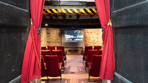 A cinema with red curtains, a stone wall, and a screen displaying various channels. - Villa in Mugello Hills with Private Pool (Vicchio)