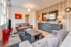 A modern living room with a grey sofa, a wooden coffee table, and a grey cabinet with a mirror.