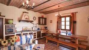 A cozy kitchen with a wooden bench, a sofa, and a table with a vase of sunflowers.