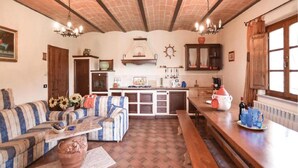 A cozy living room with a sofa, a coffee table, and a fireplace. There is a kitchen area with a stove, sink, and cabinets.