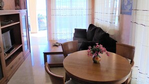 Un comedor con una mesa redonda de madera, sillas, un sofá y un aparador con un jarrón de flores.
