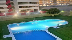 Una piscina con un césped alrededor y un edificio al fondo.