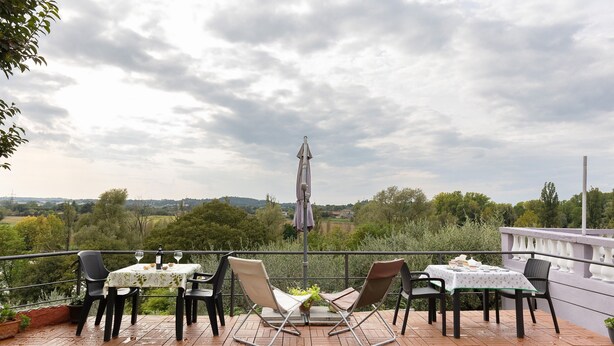 Eine Terrassengruppe mit zwei Tischen, Stühlen und einem Sonnenschirm.