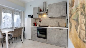 Eine moderne Küche mit grauen Schränken, einem eingebauten Backofen und einem Essbereich mit weißem Tisch und Stühlen.
