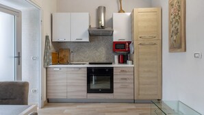 Eine kleine Küche mit Mikrowelle, Backofen und Holzschränken.