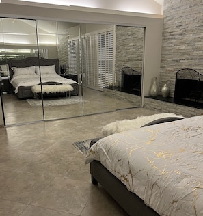 Une chambre avec un grand lit, un placard avec des portes miroir et un mur en pierre.