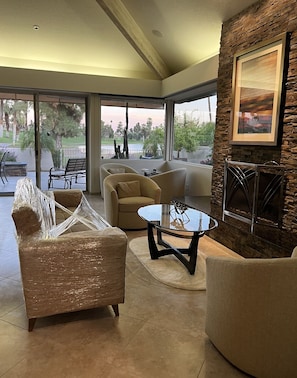 Un salon moderne avec une porte vitrée donnant sur un patio, un mur décoratif en pierre et un tableau encadré.