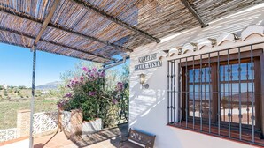 Un edificio blanco con un cartel que dice 'CORTIJO BELLAVISTA', un patio cubierto y vistas al campo.