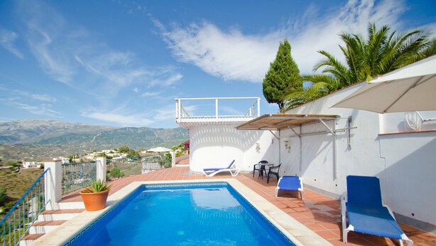 Una piscina con dos sillas de descanso, una planta en maceta y vistas al paisaje.