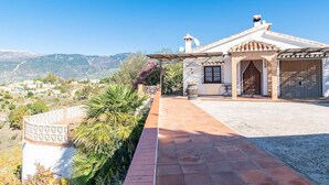 Una villa con un patio empedrado, garaje y vistas del paisaje circundante.