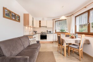 A compact kitchen with a dining area, a sofa, and a table with chairs.