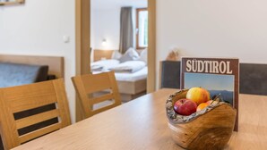 Ein Holztisch mit Obstschale und einem Schild mit der Aufschrift 'SÜDTIROL' in einem Zimmer mit Bett und Fenster.