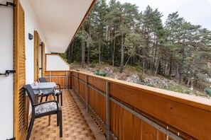 Un balcon avec une table et des chaises, donnant sur une zone boisée.