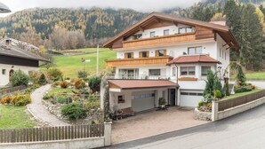 Ein mehrstöckiges Haus mit Garage, umgeben von einem angelegten Garten und einem Holzzaun.