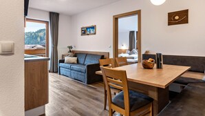 Ein modernes Wohnzimmer mit einem Holzespeisetisch, einem blauen Sofa und Blick ins Freie.