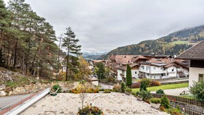 Ein Wohngebiet mit Häusern, einem gepflasterten Innenhof und einer Bergkulisse.