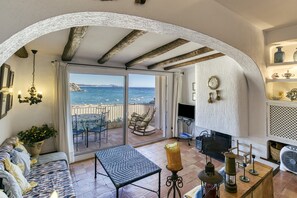 Una habitación con vista al mar, un sofá, una mesa, una lámpara y una chimenea.