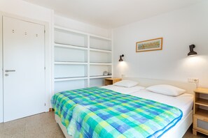 Ein Schlafzimmer mit einem Bett, einem weißen Kleiderschrank, einem Regal und Wandleuchten.