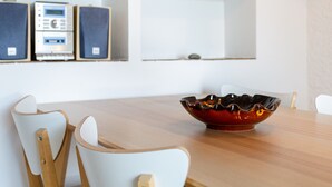 Un comedor con una mesa de madera, sillas blancas y un cuenco decorativo.