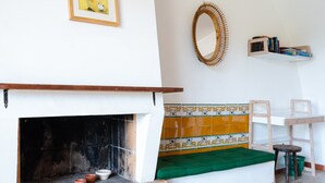 Una habitación con chimenea, un banco, un espejo y una estantería con libros.