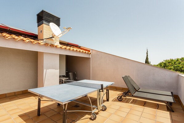Une terrasse sur le toit équipée d’une table de ping-pong, d’un fauteuil de relaxation et d’une antenne parabolique.