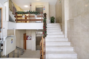 A multi-level interior with a staircase, a wheelchair-accessible lift, and a no-smoking sign.