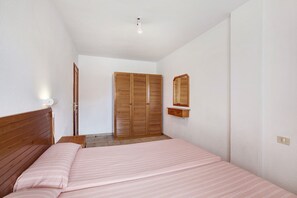 A bedroom with a bed, wooden wardrobe, and a mirror.