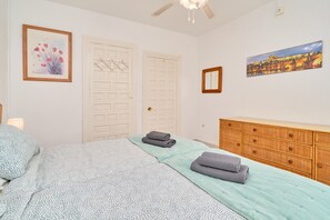 A bedroom with a bed, a dresser, a door, and a painting on the wall. - Large 1-bed Apartment with Shared Pool, Garden, A/C & Wi-Fi (Nerja)