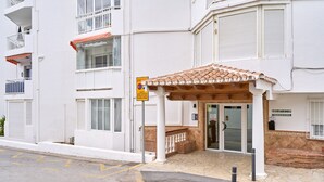 A building with a covered entrance, a sign indicating parking restrictions, and a visible entrance door.