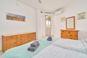 A bedroom with a bed, a wooden dresser, a mirror, and a painting on the wall. - Large 1-bed Apartment with Shared Pool, Garden, A/C & Wi-Fi (Nerja)