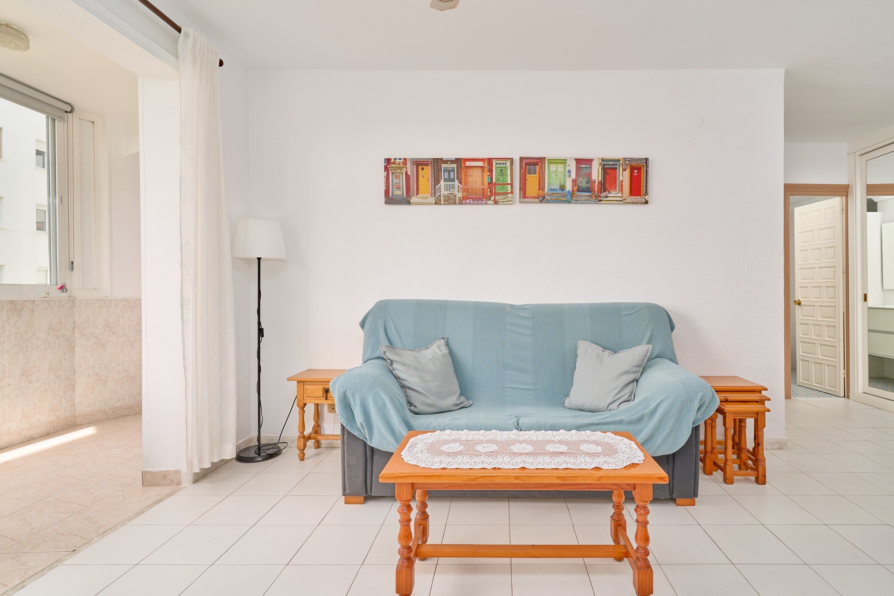 A living room with a sofa, a coffee table, a lamp, and a wall art piece.