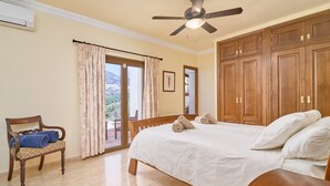 A bedroom with a bed, a chair, a ceiling fan, and wooden cabinets.