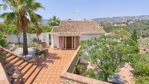 A villa with a tiled roof, a stone staircase, and a view of the surrounding landscape.