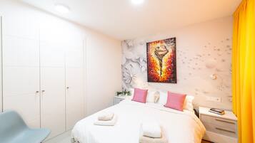 Een moderne slaapkamer met een bed, nachtkastjes, een stoel en een schilderij aan de muur.