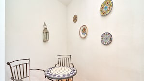 Un pequeño comedor con una mesa redonda y dos sillas, un farol colgante y tres platos decorativos en la pared.