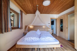 Un soffitto in legno, un letto con biancheria da letto floreale e una finestra con tende.