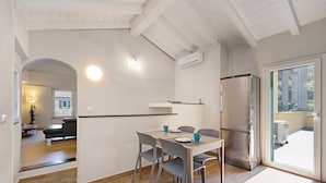 A modern kitchen with a dining area, wooden flooring, and a view through a glass door. - Ca di Perti Apartment 3 with Mountain View (Finale Ligure)
