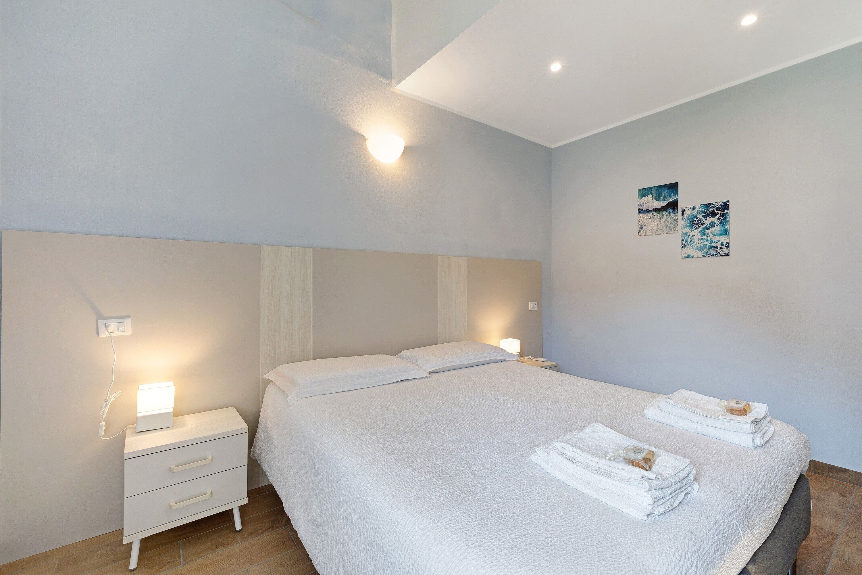 Een slaapkamer met een bed, nachtkastjes en wanddecoratie.