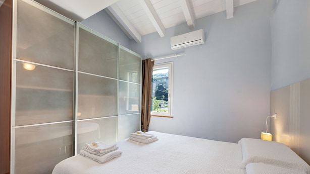 A bedroom with a bed, a large wardrobe, and a window with a view. - Ca di Perti Apartment 3 with Mountain View (Finale Ligure)