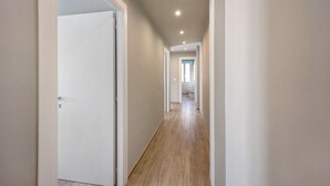 Ein Korridor mit Holzboden, weißen Wänden und Einbauleuchten.