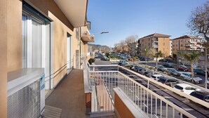 Ein Wohngebäude mit Balkon, Parkplatz und freiem Blick auf die Straße.