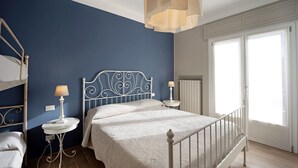 Ein Schlafzimmer mit Etagenbett, einem Einzelbett, einem runden Nachttisch mit Lampe und einem Fenster mit Aussicht.
